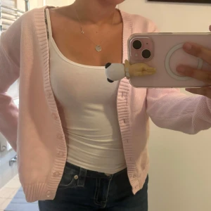 Ljusrosa kofta i bomull från Brandy melville - Supersöt ljusrosa kofta i 100% bomull från Brandy Melville . Den har v-ringning, ribbade muddar och knappar framtill. Perfekt att slänga över ett linne eller t-shirt. Långärmad och riktigt mjuk, passar till jeans eller kjol för en chill look.