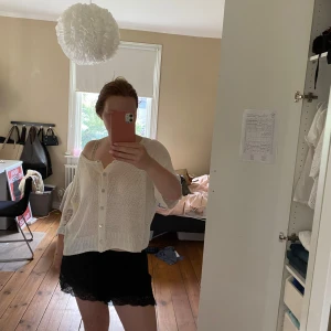 Vit kofta med spetsdetaljer och knappar - Superfin vit kofta med knappar framtill och snygga spetsdetaljer på ärmarna. Koftan är stickad i ett lätt material och har en lite loose passform med trekvartsärm. 