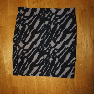 Zebramönstrad kortkjol i svart och grått/brun - Snygg kortkjol med zebramönster i svart och grått/brun. Kjolen har en rak passform och är perfekt för dig som vill sticka ut lite extra. Enkel att matcha med både sneakers och boots.