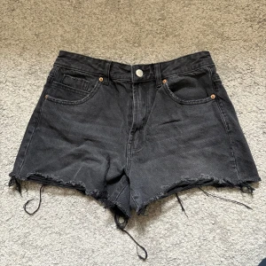 Svarta jeansshorts från Stradivarius - Svarta jeansshorts från Stradivarius med hög midja och fransiga benslut.