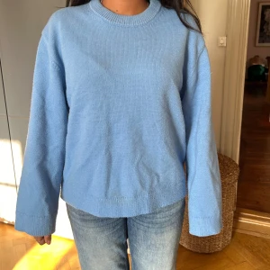 Ljusblå stickad tröja med rund hals - Enkel och snygg ljusblå stickad tröja med rund halsringning och långa ärmar. Tröjan har en avslappnad passform och ribbade muddar vid ärmslut och nederkant. Perfekt för lager-på-lager och chill dagar. Finns ej kvar och är väldigt efterfrågad. Pris är därför generöst 