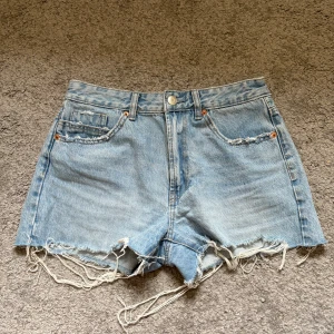 Ljusblå jeansshorts från Stradivarius - Snygga ljusblå jeansshorts från Stradivarius med medel midja och fransiga kanter. 