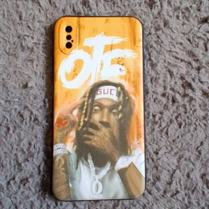 Färgglatt OTF mobilskal med motiv - Säljer ett unikt mobilskal med OTF-tryck och coolt motiv på baksidan. Skalet har en gul-orange bakgrund och detaljer i vitt och svart. Passar till mobil med dubbla kameror. Materialet är troligtvis syntet och skalet är lätt och smidigt.