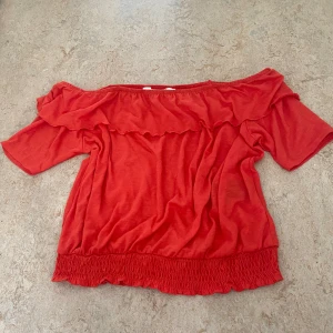 Offshoulder topp - Snygg röd offshoulder topp från H&M med volangdetalj upptill och smockad nederkant. Toppen har korta ärmar. Det är en barnstorlek men funkar perfekt även till någon med XS o S🥰💕