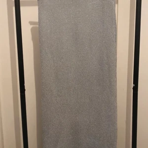Glittrig silverkjol från Gina Tricot - Supersnygg glittrig silverfärgad kjol från Gina Tricot. Kjolen är kort och har en rak, tight passform. Materialet är stickat och skimrar snyggt i ljuset – perfekt för att sticka ut. Enkel design utan detaljer, men ändå riktigt trendig.
