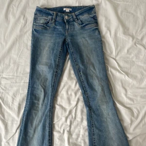 Blå bootcut jeans från Gina Tricot - Snygga blå low waist bootcut jeans från Gina Tricot i klassisk denim med ljus tvätt. Femficksmodell med dragkedja och knapp framtill. Köpta i vintras och har super bra skick 
