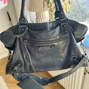 Balenciaga city bag - Äkta balenciaga city bag, i en mörkgrön/gråaktig färg! Superfin. Spegeln saknas!!Det är en begagnad väska som har använts. Inga större slitningar eller liknande finns. Storlek medium. Första bilderna är lånade från förra ägaren. Kan även tänka mig byta mot annan färg, börjar bli sugen på något nytt!🥰
