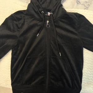 Svarta mjukisbyxor med snörning - Svarta mjukisbyxor i mjukt och lent material med bekväm resårmidja och snörning framtill. Perfekta för chill dagar eller när du vill vara extra comfy. Byxorna har en enkel och stilren look som passar till hoodie eller t-shirt. Kofta och byxorna i storlek S.