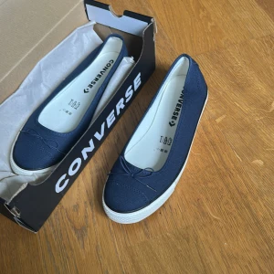 Mörkblå ballerinaskor Converse NYA  - HELT OANVÄNDA!! Beställde två olika storlekar och gick sedan inte att skicka tillbaka dessa jag inte valde.. Snygga mörkblå ballerinaskor från Converse i canvas med vit sula och liten rosettdetalj framtill. Skorna har rund tå och klassisk Converse-logga på innersulan. Perfekta till jeans eller kjol! storleken står 40,5, men är små storlekarna så skulle säga att det passar 39,5 eller 40 mera. ny pris: 750 kr