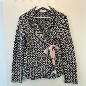 Mönstrad kofta från Odd Molly med rosett - Superfin svart och vit kofta från Odd Molly med snyggt grafiskt mönster och ljusrosa knytband i sidan. 