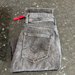 Grå jeans från Replay - Snygga grå jeans från Replay med en super slim passform. De har en klassisk femficksdesign och är tillverkade i ett slitstarkt material. Endast använda ett fåtal gånger. Perfekta för en grish look, säljer de för att de kom i fel storlek. Det står 158 men passar folk som är 170. Skriv för fler frågor!