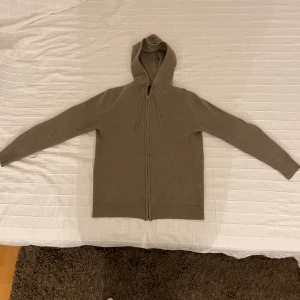 Beige stickad zip up hoodie - Säljer en stilren beige stickad hoodie med dragkedja framtill. Tröjan har en praktisk huva med dragsko och långa ärmar. Perfekt för kyliga dagar! Storlek S och den är knappast använd, 100% ull. Sjukt bra kvalitet 