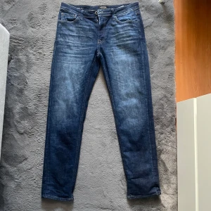 Mörkblå tapered jeans från Jack & Jones - Snygga mörkblå jeans från Jack & Jones | Nypris 899kr | strl 32 32 men passar nog bäst i lite mindre storlek eftersom den har tvättats fåtal gånger | Jeansen är använda några gånger men inte några defekter alls | Modellen är jjmike vilket då är en Tapered Jeans modell.