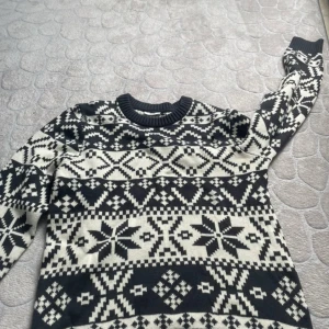 Svartvit stickad tröja Kappahl - Snygg stickad tröja från Kappahl i svart och vitt med klassiskt nordiskt mönster. Rund hals och långa ärmar, perfekt för kalla dagar. Mjuk och skön känsla, passar dig som gillar stilrena vintervibes och grafiska detaljer. Storlek S