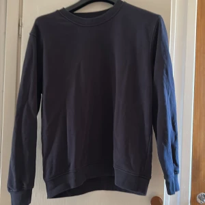 Mörkblå sweatshirt från Newbody L - En basic mörkblå sweatshirt från Newbody i storlek L. Tröjan har rund hals, ribbade muddar vid ärmslut och nederkant samt lång ärm. Perfekt för en chill och enkel stil. 