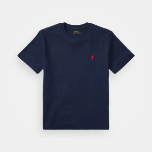Marinblå t-shirt från Polo Ralph Lauren - Klassisk marinblå t-shirt från Polo Ralph Lauren med korta ärmar och rund hals. T-shirten har en liten röd broderad logga på bröstet och är gjord i mjuk bomull. Perfekt för en clean och stilren look.