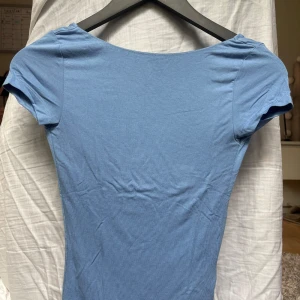 Blå topp med öppen rygg från Gina Tricot - Supersnygg blå topp från Gina Tricot i storlek XXS. Modellen är tight med korta ärmar och har en riktigt djup, rundad rygg som ger en cool look. Tunt och stretchigt material som sitter skönt på kroppen. Perfekt att styla med jeans eller kjol. Använd några enstaka gånger!! Kontakta om du har funderingarna!!❤️