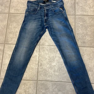 Replay Anbass blå jeans slim fit, 28/30 - Snygga blå Replay Anbass jeans med slim fit och klassisk femficksdesign. Jeansen har en lätt tvättad look, dragkedjegylf och diskreta detaljer på bakfickorna. Perfekta för dig som gillar en modern och stilren denimstil. Använda fåtal gånger                                                                              