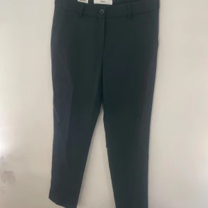 Mörkblå kostymbyxor från Brax - Snygga mörkblå kostymbyxor från Brax, modell Maron. Byxorna har normal passform, raka ben och klassiska detaljer som bälteshällor, sidfickor och bakfickor med knapp. Perfekta för en clean och stilren look.