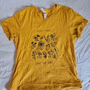 T-shirt: plant these save the bees - Söt gul t-shirt i bomull med svart blommigt tryck och texten 'Plant these, save the bees'. Denna tshirt var THE SHIT om du var tumblr/pinterest art h-e aesthetic ca 2018, dsvdv. Obs, är hemma-fållad i nederkanten! Färgen är mer som i de två utzoomade bilderna.
