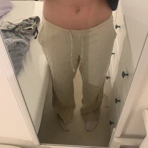 Beiga linnebyxor från Gina Tricot - Säljer ett par beiga linnebyxor från Gina Tricot med avslappnad passform och dragsko i midjan. Byxorna är raka i modellen och har elastisk midja för extra komfort. Perfekta för varma dagar när du vill ha en chill och stilren look. Använda 1-2 gånger. Det är en liten fläck på låret men syns inte när man har på säg dom!! Stor i storleken. Väldigt långa. Jag är ca 167 och dom är långa på mig!
