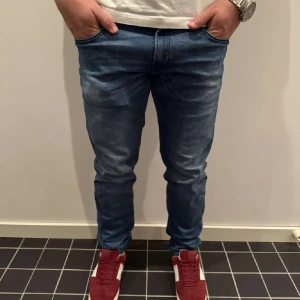 Blå Replay Anbass jeans slim fit - Säljer ett par blå Replay Anbass jeans med slim fit och klassisk femficksdesign. Jeansen har snygga slitningar och en tydlig Replay-patch bak på linningen. Perfekta för dig som gillar en modern och smal siluett. Materialet är mjukt och stretchigt jeans.