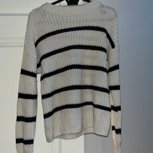Randig stickad tröja från Lager 157 - Säljer en stickad tröja från Lager 157 i storlek S med svarta ränder. Tröjan har en rundad hals och långa ärmar.