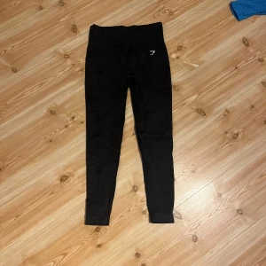 Svarta leggings från Gymshark - Säljer ett par svarta leggings från Gymshark med hög midja och diskret mönster. Har en liten buttscrunch!