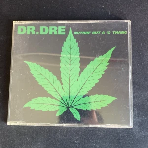 Nuthin' But a 'G' Thang - Klassisk CD-singel från Dr. Dre med den ikoniska låten 'Nuthin' But a 'G' Thang'. Perfekt för dig som gillar hiphop och vill ha en bit av musikens historia i samlingen. Coolt omslag med grön bladgrafik och flera mixar av låten på skivan.