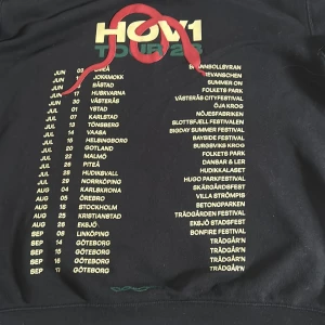 Svart Hov1 hoodie med tour-tryck - Svart hoodie från Hov1 i storlek M med broderad krona på bröstet och stort tour-tryck på ryggen. Tröjan har huva med snörning och en stor magficka. Mjuk insida i fleece och klassisk loose passform. Säljer för jag inte har använt den så mycket 
