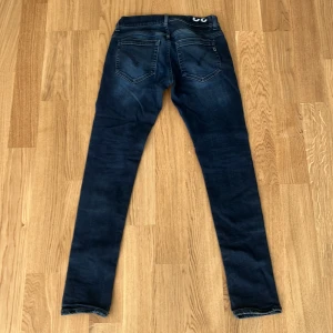 Mörkblå skinny jeans från Dondup - Snygga mörkblå jeans från Dondup, modell George, tillverkade i Italien. De har en skinny passform med klassiska fem fickor och subtila slitningar för en cool look. Materialet är jeans och midjan är normal. Perfekta för dig som gillar stilrena och tajta jeans.
