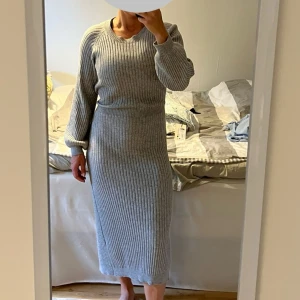 Grå ribbad långklänning Bubbleroom - Säljer en snygg grå långklänning från Bubbleroom i ribbstickad kvalitet. Klänningen har lång ärm, rund halsurringning. Snöret går att knyta fram och bak. 