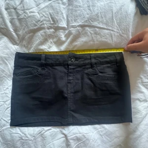 Svart jeanskjol med broderade fickor - Svart Lågmidjad jeanskjol, storlek 36