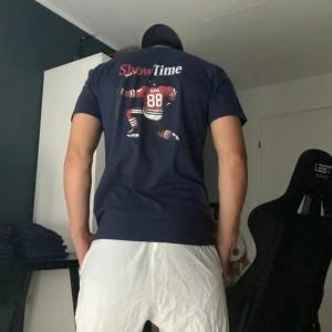 Showtime t-shirt  - Egendesignad Patrik Kane T-shirt Visa ditt stöd för en av hockeyns största stjärnor med denna unika t-shirt med Patrik Kane! T-shirten har en personlig och streetinspirerad design som du inte hittar någon annanstans – perfekt för både vardag och matchdag.  Finns i storlekarna S, M och L. Pris: 299 kr. Begränsat antal – passa på innan de tar slut!