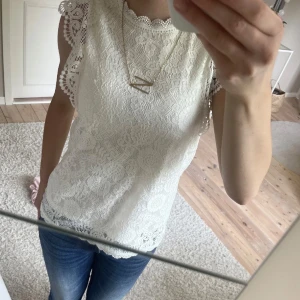 Vit spetsblus med volangärmar - Superfin vit blus med spets och detaljerade volangärmar. Blusen har ett romantiskt mönster och är ärmlös med rund hals. Är jätte snygg att ha lager på lager (kolla bilder ovan)💞💞 Passar till både jeans och kjol för en fräsch look. 