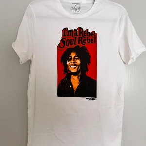 Wrangler x Bob Marley vit t-shirt S - Vit t-shirt från Wrangler x Bob Marley med tryck i rött, svart och gult på framsidan. Motiv med texten 'I'm a Rebel Soul Rebel' och Bob Marley. Rund hals och korta ärmar. Mjuk bomullskvalitet, klassisk passform.