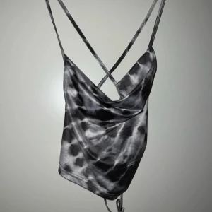 Svartgrå/silvrig drop neck linnetopp - Säljer en snygg svart och grå/silvrig linnetopp med drop neck & snöre bak 