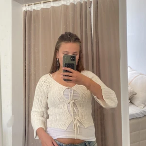 Vit stickad kofta med knyt från Kappahl - Superfin vit stickad kofta från Kappahl i storlek XS. Koftan har trekvartsärmar, snygg v-ringning och knyt framtill. Perfekt att slänga över ett linne för en chill och trendig look. Lätt och luftig, passar grymt till både jeans och kjol.