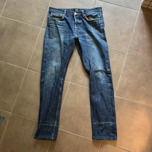 A.P.C. Petit Standard jeans blå 31 - Säljer ett par klassiska A.P.C. Petit Standard jeans i blå denim. Modellen har raka ben, fem fickor och snygga kontrastsömmar. Jeansen är tillverkade i robust bomullsjeans och har en stilren, tidlös look som funkar till det mesta.
