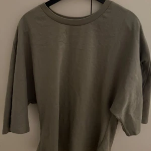 Olivgrön loose tröja från lager 157 - Olivgrön tröja från lager 157 i storlek M. Modellen är tight fit vid midjan med rund hals och lite längre fladdrande ärmar. Materialet är mjuk bomull som känns skönt mot huden. Perfekt för dig som gillar enkel och clean stil.