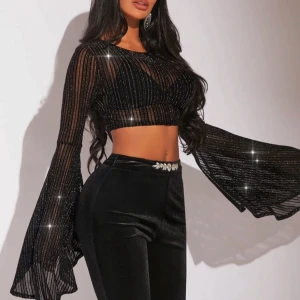 Glittrig svart croppad blus - Supersnygg svart glittrig blus med vida trumpetärmar och croppad passform. Aldrig använt så helt nytt skick! Hör av er för fler bilder☺️