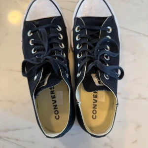 Svarta Converse All Star sneakers - Snygga converse med lite platform i i princip nyskick men har gått sönder lite på högra skon som man kan se på bilderna då jag har satt på mig skorna utan att ta av sko snöret, men absolut inget man märker av eller påverkar passformen. Storlek 37 men är stora is toleken så de passar mig som har 37,5-38.