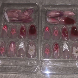Rosa och blommiga lösnaglar - Säljer flera set med lösnaglar i olika rosa och nude nyanser, dekorerade med 3D-blommor, pärlor och guldiga detaljer. Naglarna har både spetsig och rundad form och kommer i olika storlekar. Perfekt för dig som vill ha en söt och kreativ nagelstil.