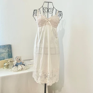 Champagnefärgad nattlinne med spetsdetaljer och rosett - Söt nattlinne i champagnefärg med spetsdetaljer över bysten och längst ner. Ganska genomskinlig på den nedre delen. Storlek: XS-S (34-36). Byst: 80-90cm. Dockans storlek: 34.