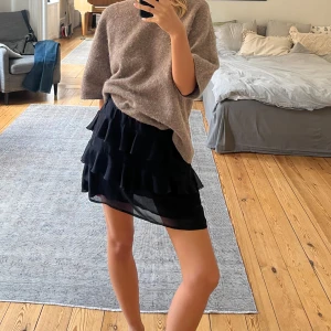 Svart volangkjol från PrettyLittleThing - Supersöt svart kortkjol med flera lager volanger från PrettyLittleThing. Kjolen har två små defekter, men dessa syns inte när kjolen sitter på. Annars är den i mycket bra skick. 