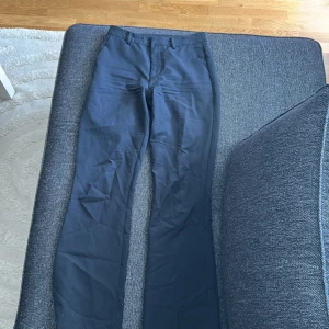Svarta kostymbyxor från Bikbok  - Snygga svarta kostymbyxor med klassisk bootcut och pressveck. Byxorna har hällor för bälte, sidofickor fram och passpoalfickor bak. Materialet känns slätt och har en lätt glans. 