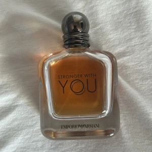 Emporio Armani Stronger With You parfym - Emporio Armani Stronger With You är en elegant parfym i en stilren, fyrkantig glasflaska med rundad silverfärgad metallkork. Doften har en varm bärnstensfärgad vätska och flaskan har tydlig logga framtill. Perfekt för dig som gillar exklusiva och moderna dofter. Den har cirka 70-75 ml kvar i flaskan.
