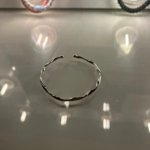 Silvrigt tvinnat armband - Snyggt armband i silverfärgad metall med tvinnad design och öppet avslut. Perfekt för dig som gillar minimalistiska och stilrena smycken med en twist. Passar att bära ensam eller att kombinera med andra armband för en personlig look.
