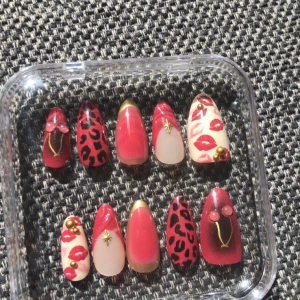 Färgglada lösnaglar med leopardmönster - Snygga lösnaglar i rött, nude och guld med coola detaljer som leopardmönster, läppavtryck, stjärnor och små pärlor. Mix av matta och glansiga ytor, vissa med guldiga linjer och 3D-effekter. Perfekt för dig som vill sticka ut med din nagelstil.
