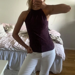Halterneck topp  - Säljer en glittrig lila halterneck topp med snygg knytning i nacken och öppen rygg. 